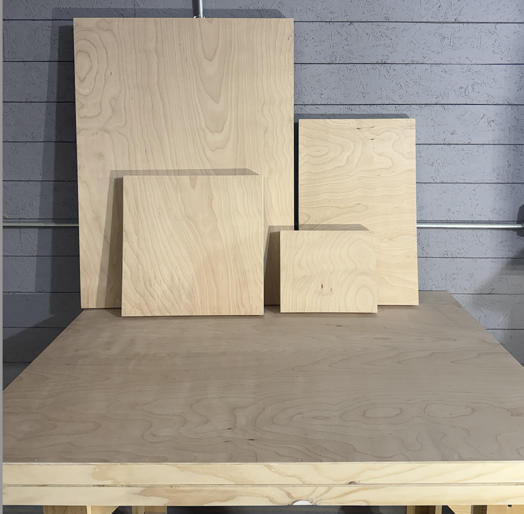 Multiple sizes of handcrafted birch painting panels leaning against workshop wall
